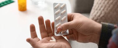 Evinde haplardan su toplayan bir adam, yakın plan.