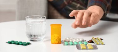 Hasta adam masadan hap alıyor, yakın plan.