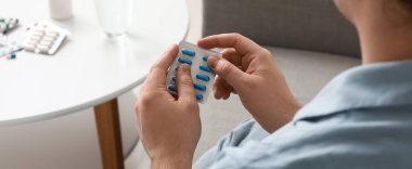 Evinde haplardan su toplayan genç adam, yakın plan.