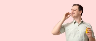 Mutlu genç adam pembe arka planda haplar alıyor, mesaj için yeri var.