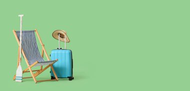 Güverte sandalyesi, kürek, şapka ve bavul yeşil arka planda mesaj için yer var. Yaz tatili kavramı