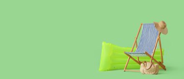 Güverte koltuğu, şişme yatak, plaj çantası ve yeşil arka planda mesaj için yeri olan şapka. Yaz tatili kavramı