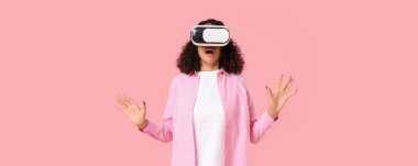 Şaşkın Afro-Amerikalı kadın pembe arka planda VR gözlük takıyor.