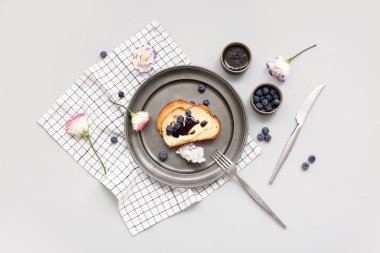 Lezzetli reçelli tost tabağı, gri arka planda yabanmersini ve çiçekler.