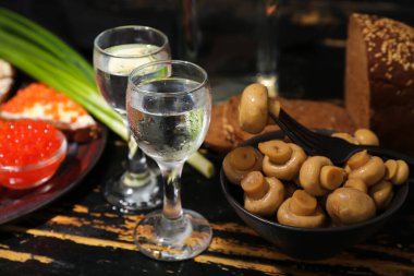 Soğuk votka ve siyah ahşap arka planda atıştırmalıklar.