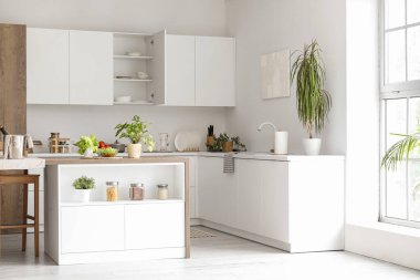 Beyaz tezgahlı ve ada masalı modern mutfağın içi.