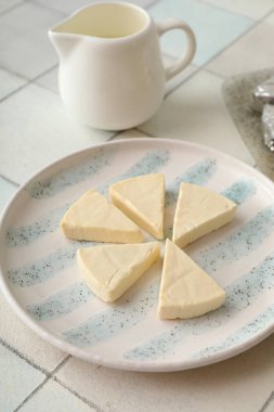 Açık fayans zemin üzerinde lezzetli işlenmiş peynir üçgenleri olan tabak, yakın plan.