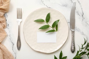 Boş davetiye kartı ile güzel masa ayarları ve beyaz masa üzerine bitki dalları