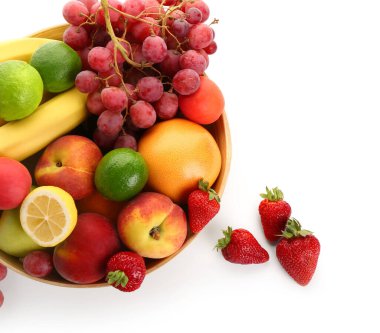 Beyaz arka planda farklı taze meyveler olan bir kase.