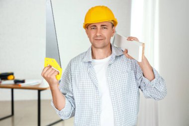 Eltestereli ve odasındaki ahşap tahtalarla olgun bir inşaatçı.