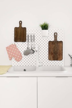 Kesme tahtaları, tahta, lavabo ve çatal bıçakları olan beyaz mutfak tezgahları.