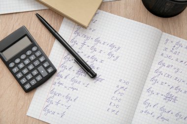 Hesap defterini matematik formülleri ve hesap makinesiyle ahşap masada aç