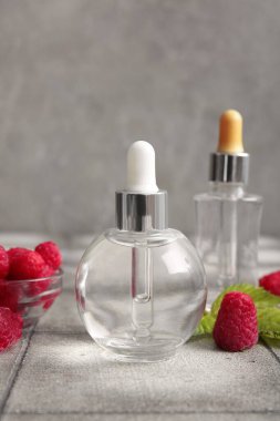 Kozmetik ahududu yağı ve gri kiremit masasında böğürtlen dolu bir kase.