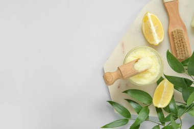Bir kase limonlu vücut fırçası ve gri arka planda masaj fırçası.