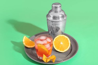 Bir bardak soğuk Negroni kokteyli, arkaplanda turuncu ve sallanan.