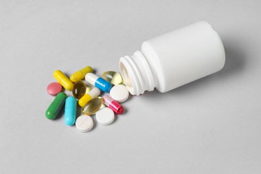 Gri arka planda farklı dağılmış haplarla dolu kavanoz.