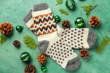 Kozalaklı çoraplar, yeşil arka planda Noel topları ve koniler.