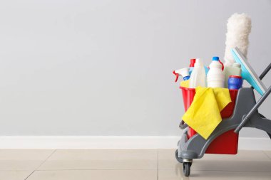 Aydınlık duvarın yanında temizlik malzemeleri olan bir araba.