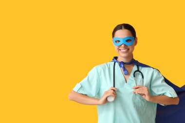 Sarı arka planda süper kahraman kostümlü genç bayan doktor.