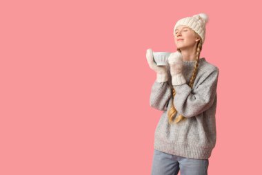 Pembe arka planda bir fincan çayı olan güzel, genç ve mutlu bir kadın.