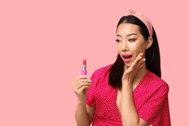 Pembe arka planda ruj izi olan güzel, şaşırmış Asyalı kadın.