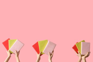 Pembe arka planda kitapları tutan eller