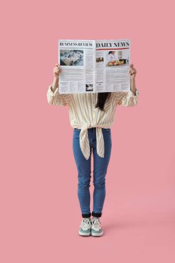 Pembe arka planda gazete okuyan genç bir kadın.
