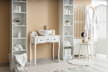 Lavabosu ve raf üniteleri olan şık bir banyo.