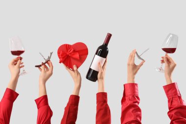 Kırmızı şarap, hediye ve arka planda tirbuşonu olan kadınlar. Sevgililer Günü kutlaması