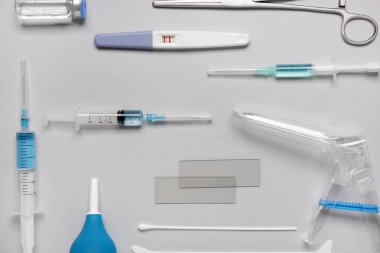 Beyaz zemin üzerinde pap smear test araçları, şırıngalar ve ampul içeren jinekolojik spekulum