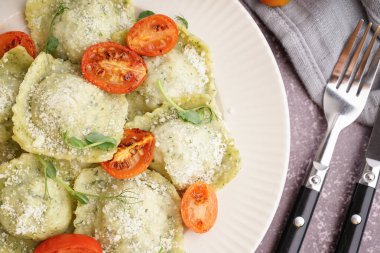 Gri arkaplanda domatesli ve peynirli lezzetli ravioli tabağı