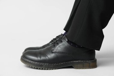 Gri arka planda siyah şık ayakkabılı genç adamın bacakları.