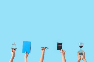 Kum saati tutan kadın eller, adalet terazisi, pasaport ve mavi arka plan üzerine kitap.