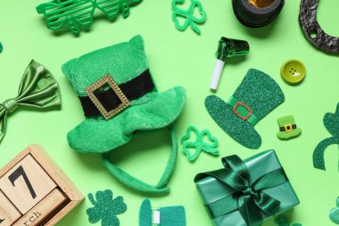Yeşil arka planda Aziz Patrick Günü için takvime, hediye kutusuna ve dekora sahip leprikon şapka.