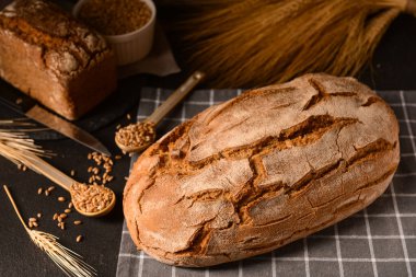 Buğday dikenli somunlar ve siyah arka planda tahıllar