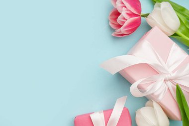 Hediye kutuları ve mavi arka planda güzel laleler.