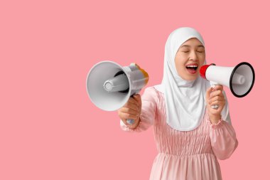 Genç Asyalı Müslüman kadın pembe arka planda megafonlara bağırıyor. Ulusal Duyulma Günü