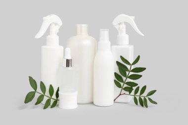 Kavanozlu kompozisyon, kozmetik ürünleri şişeleri ve gri arkaplanda dallar