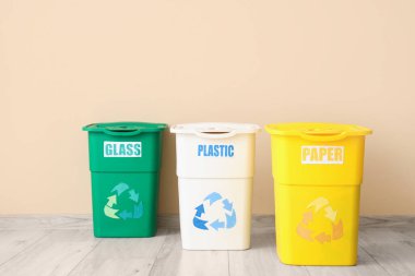 Bej duvarın yakınındaki farklı çöp kutuları için boş çöp kutuları. Geri dönüşüm kavramı