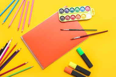 Not defteri ve suluboya resimler sarı arka planda. Üst görünüm