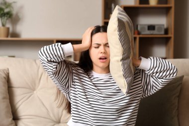 Yastıklı genç kadın evinde şiddetli baş ağrısı çekiyor.