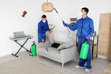 Koruyucu giysiler içindeki erkek işçiler dezenfekte odasında.