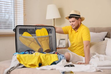 Erkek turist otel odasında bavulunu boşaltıyor.