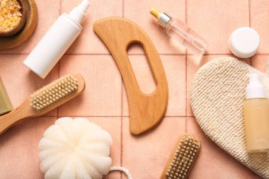 Ahşap guasha vücut masajı aracı, banyo süngeri ve pembe karo arka plan eldiveni ile kompozisyon