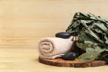 Ahşap zemin üzerinde gerekli yağ, havlu ve meşe saunası olan tahta bir tahta.