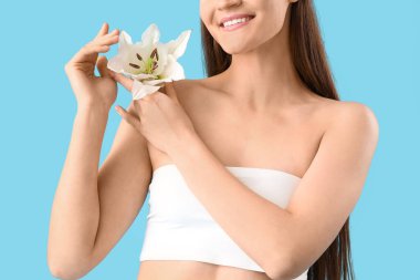 İç çamaşırlı, mavi arka planda beyaz zambak çiçeği olan genç ve güzel bir kadın.