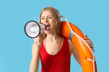 Kurtarma yüzüğüyle mavi arka planda megafonla bağıran genç bir kadın cankurtaran.