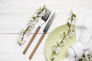 Beyaz ahşap arka planda çiçek açan dalları olan güzel bir masa.