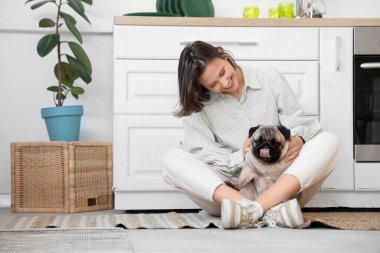 Mutfakta yerde oturan sevimli köpekli genç bir kadın.
