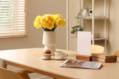 Oturma odasının iç tarafındaki yemek masasında güzel narsis çiçekleri olan vazo.